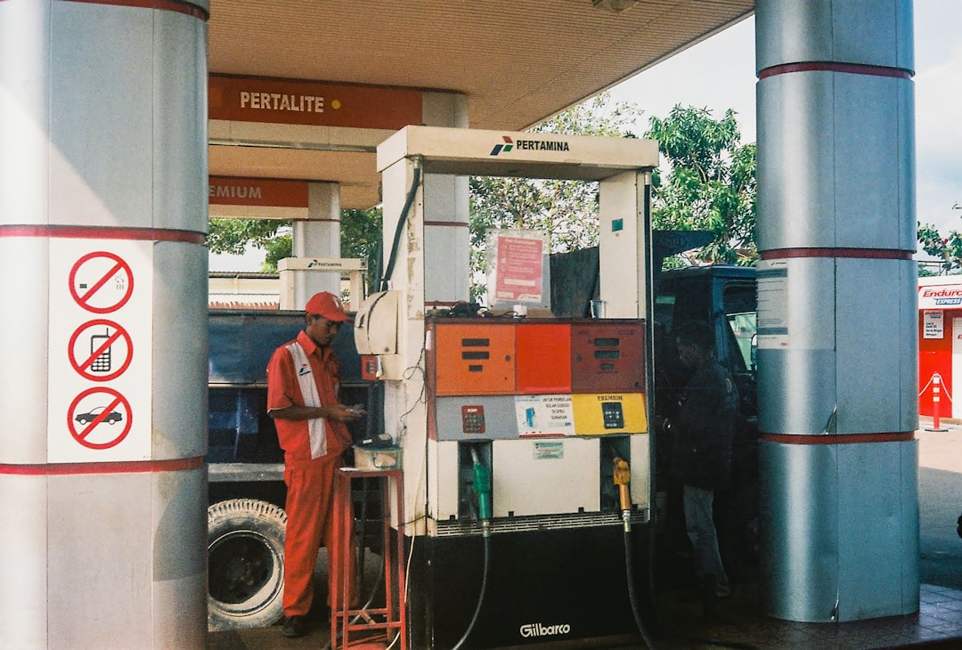 man in red and black plaid dress shirt standing near gas pump