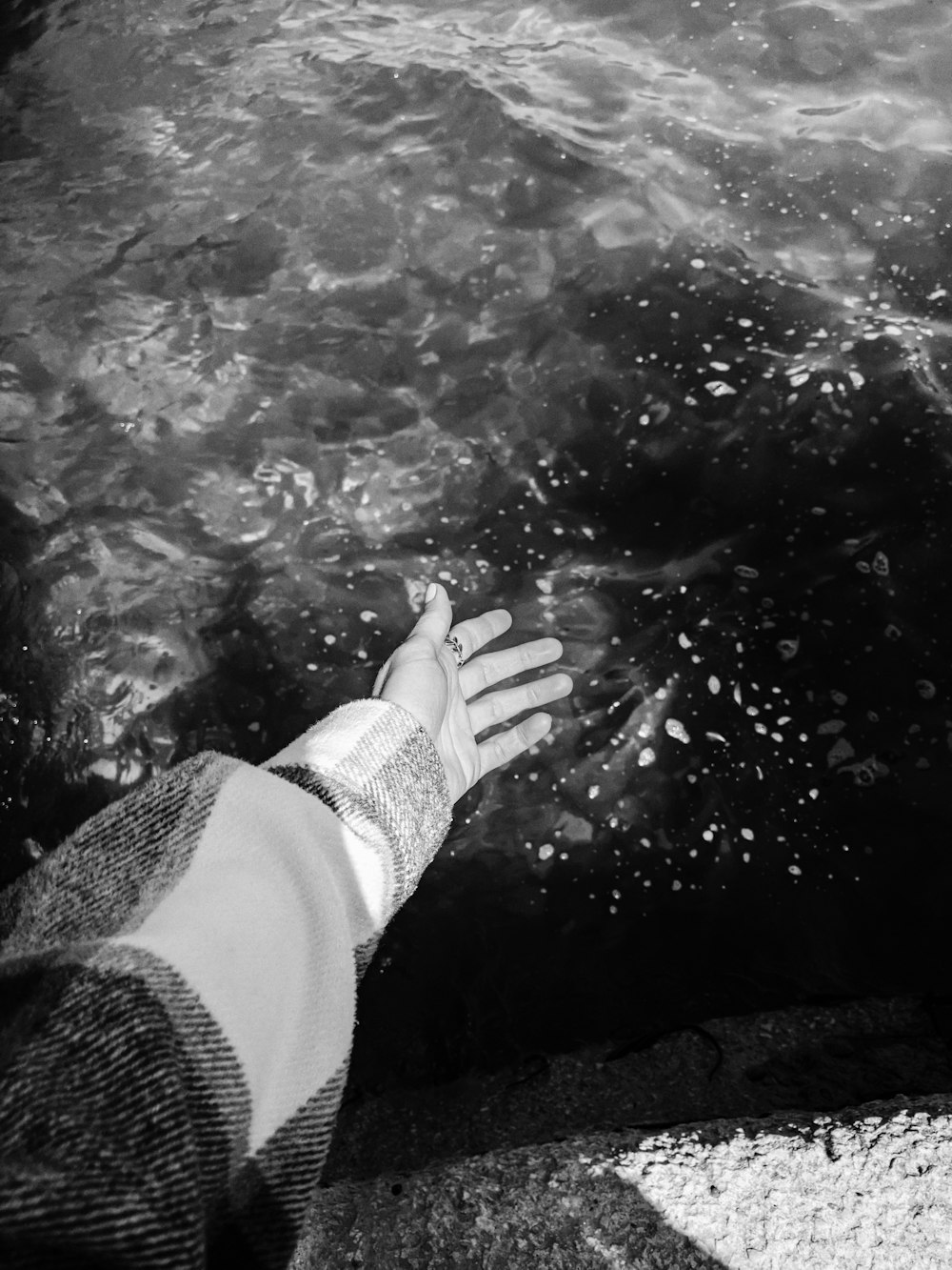 person in black long sleeve shirt and white pants in water