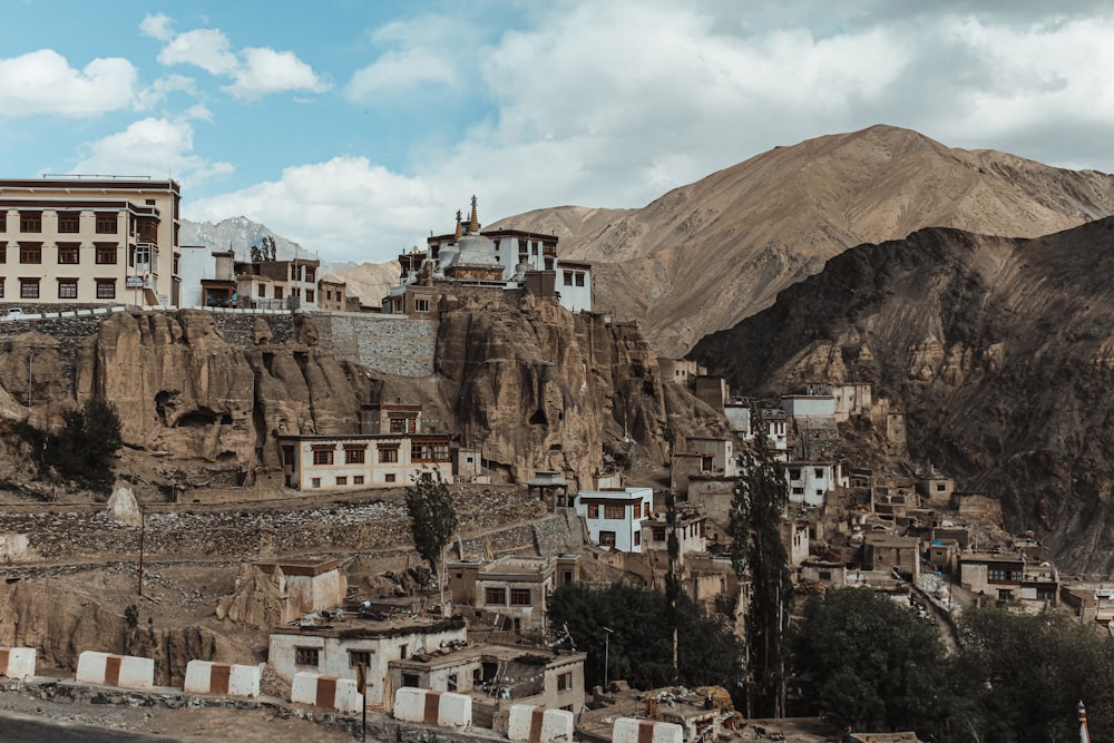 brown and white concrete buildings near brown mountain under white clouds during daytime