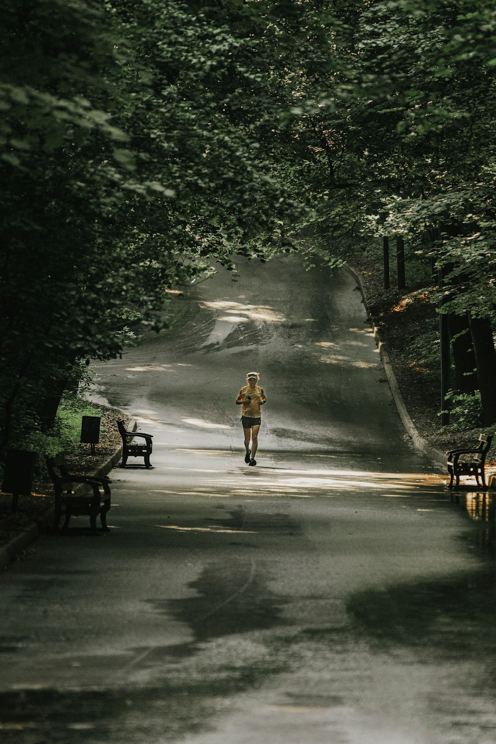 person in yellow jacket and black pants walking on road during daytime