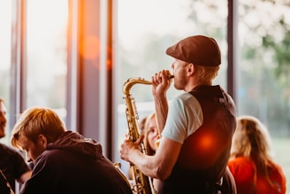 man in white crew neck t-shirt playing saxophone during sunset