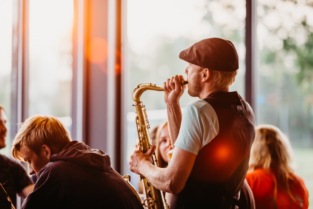 man in white crew neck t-shirt playing saxophone during sunset