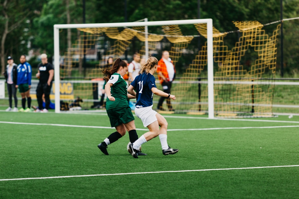 昼間、緑のグラウンドでサッカーをする女性たち