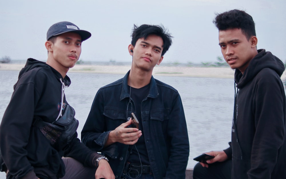 man in black jacket and blue cap sitting beside man in black jacket