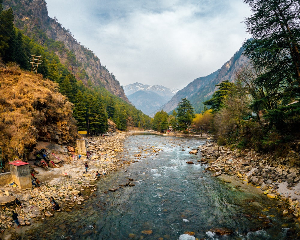 river between green mountains under white cloudy sky during daytime