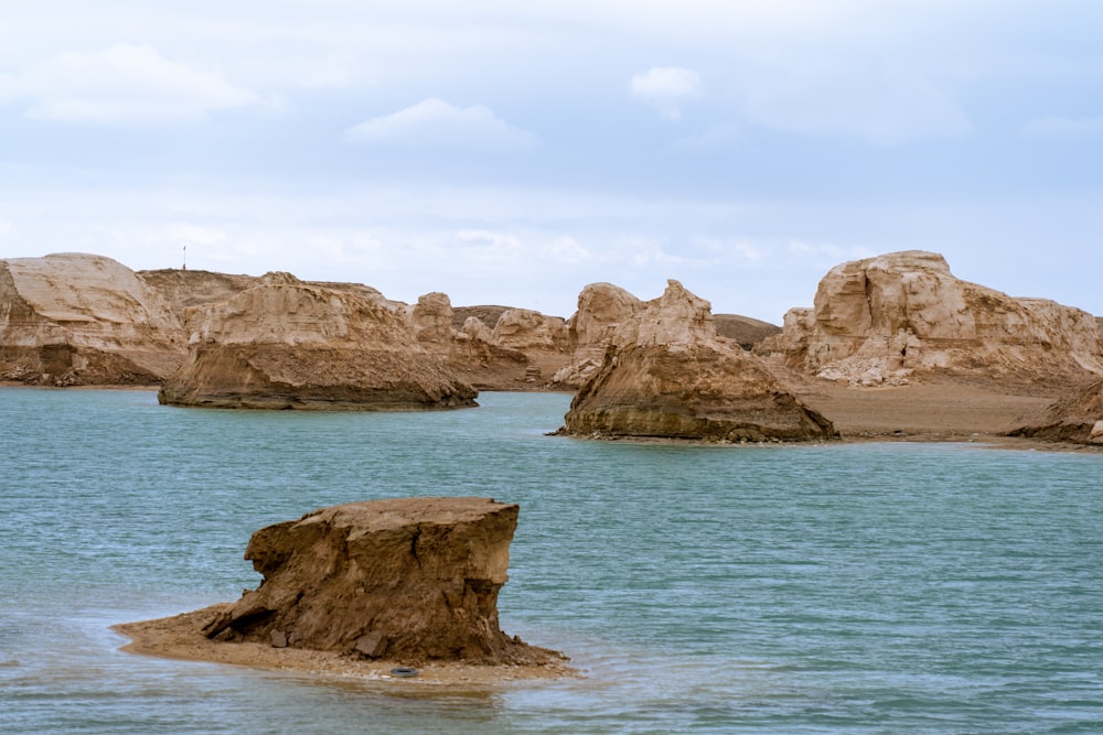 brown rock formation on blue sea under white sky during daytime