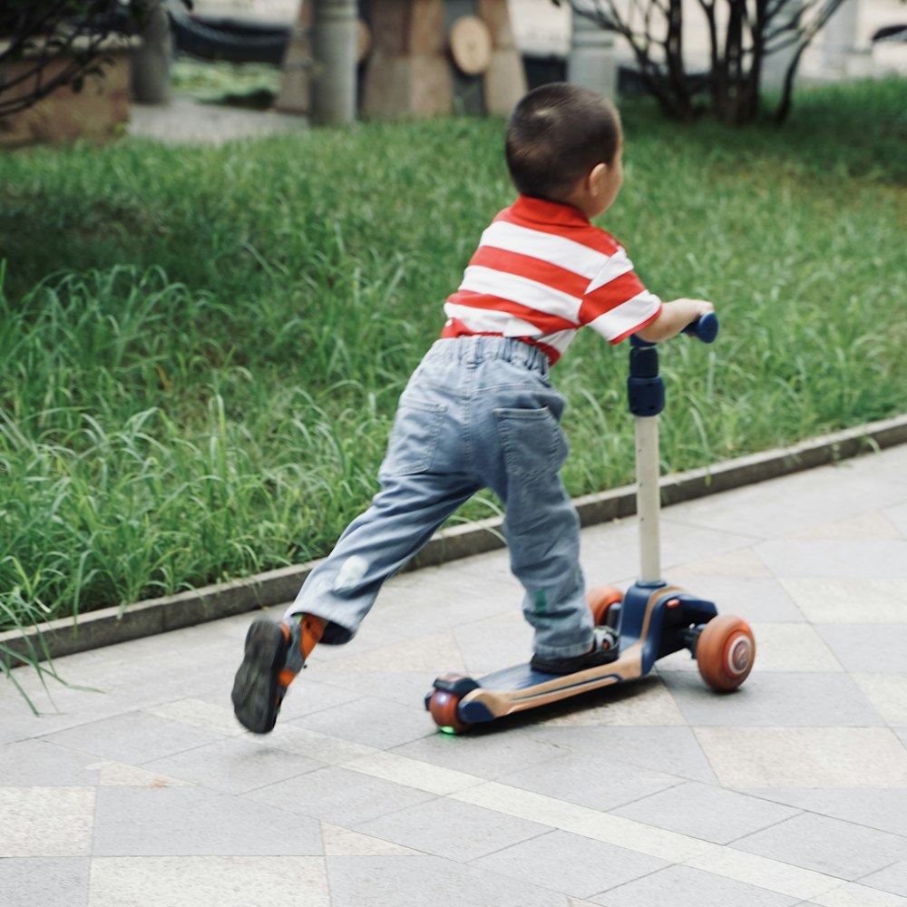 boy in red and white striped shirt and blue denim jeans playing red and black kick