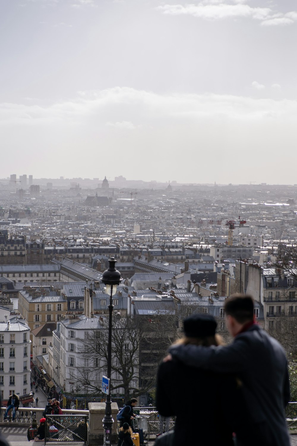 man in black jacket standing on top of building looking at city during daytime