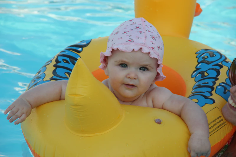A baby splashing in the pool with a parent during a Baby & Me class