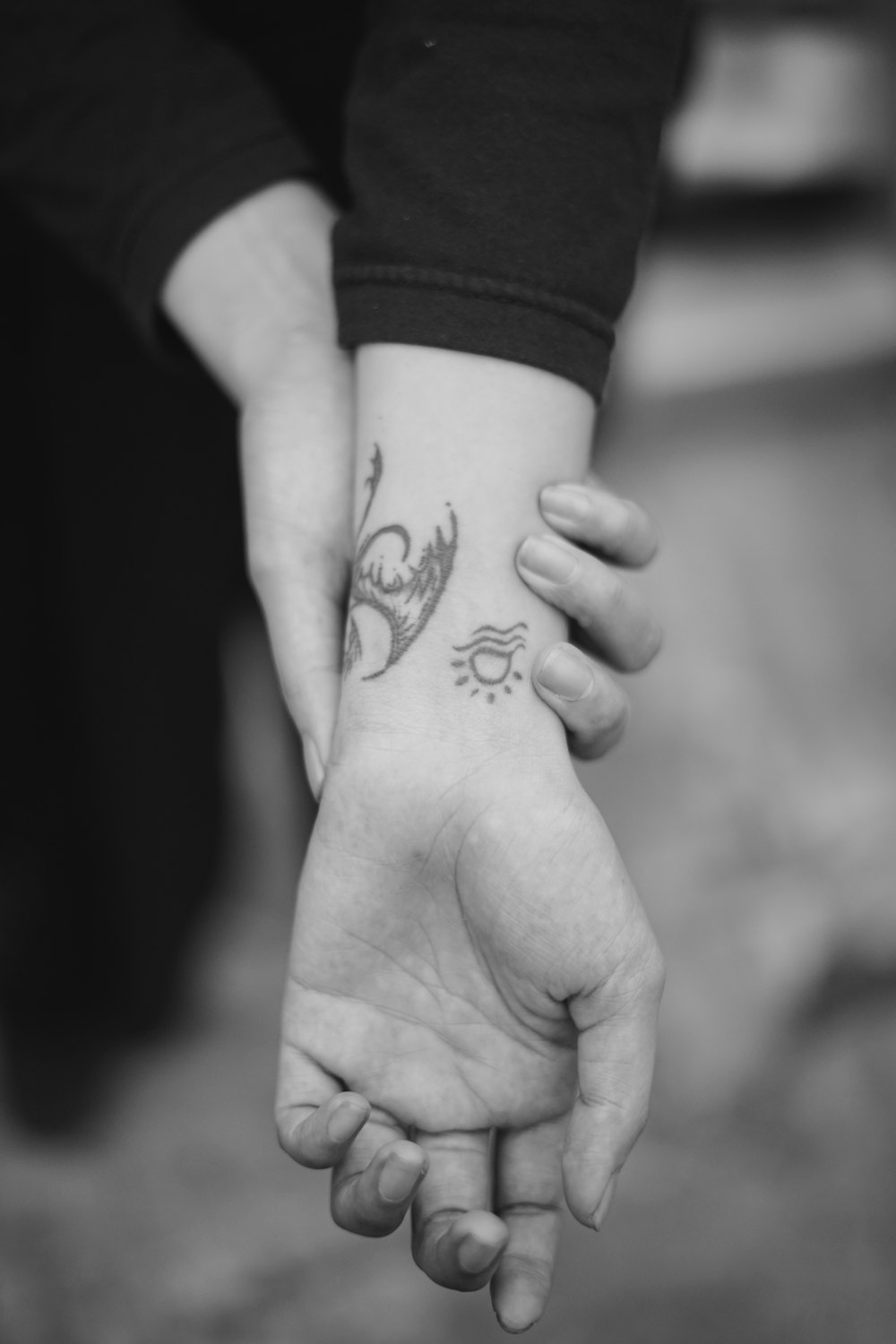foto em tons de cinza da mão humana com tatuagem