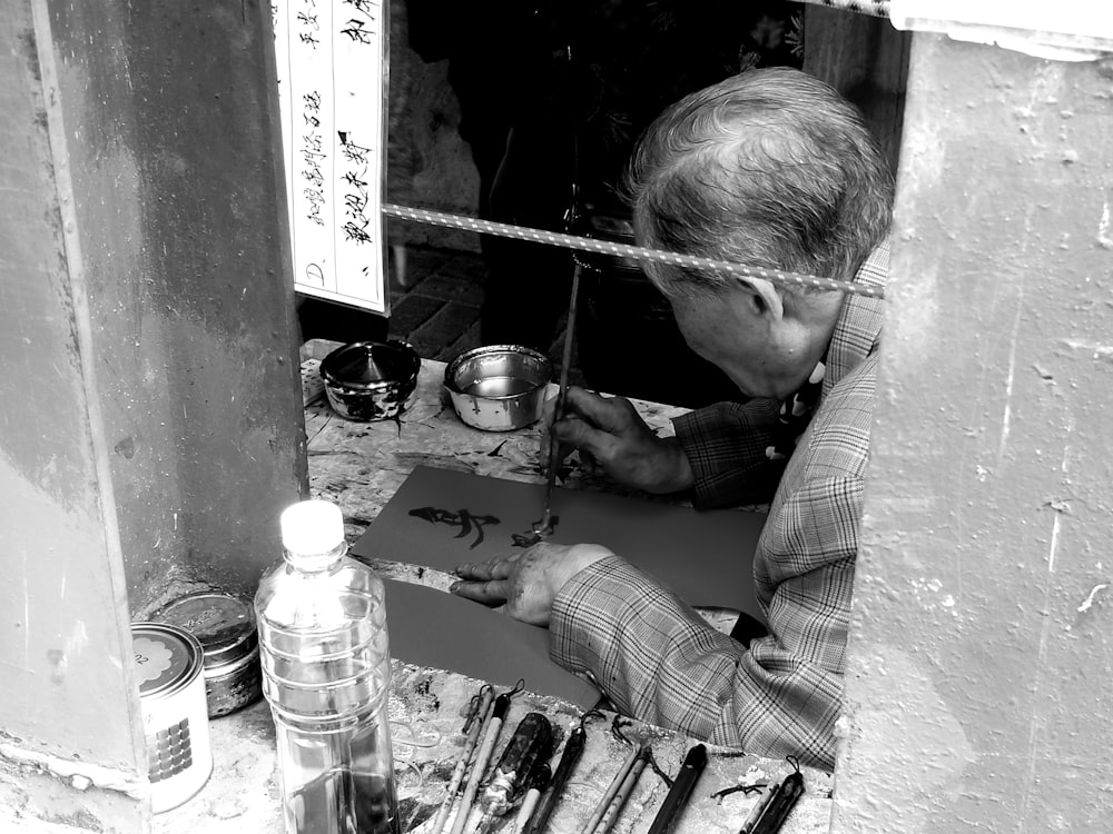 grayscale photo of man writing on paper