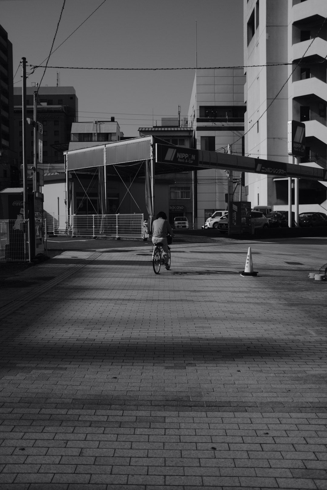 grayscale photo of man riding bicycle on road