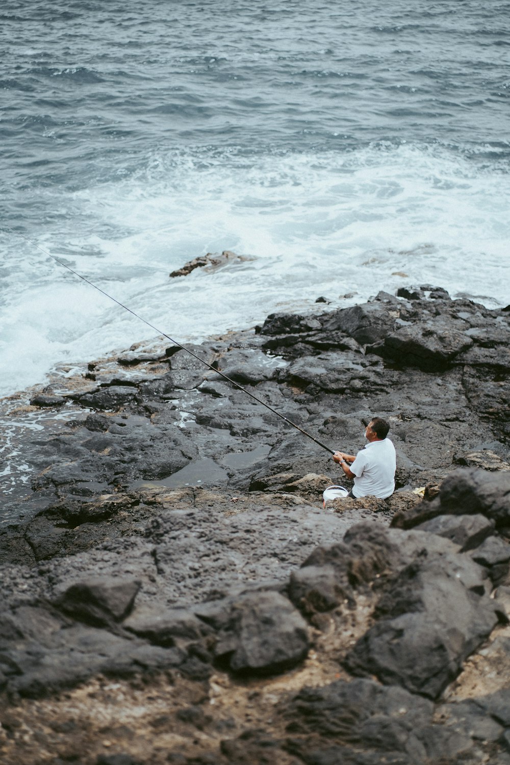 man in white long sleeve shirt fishing on sea during daytime