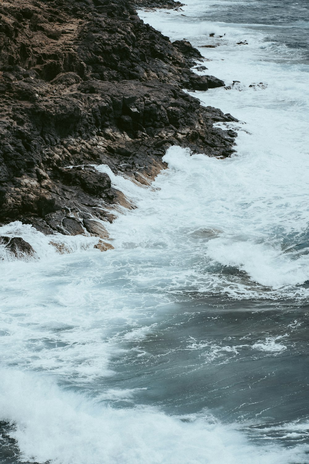 ocean waves crashing on rocky shore during daytime