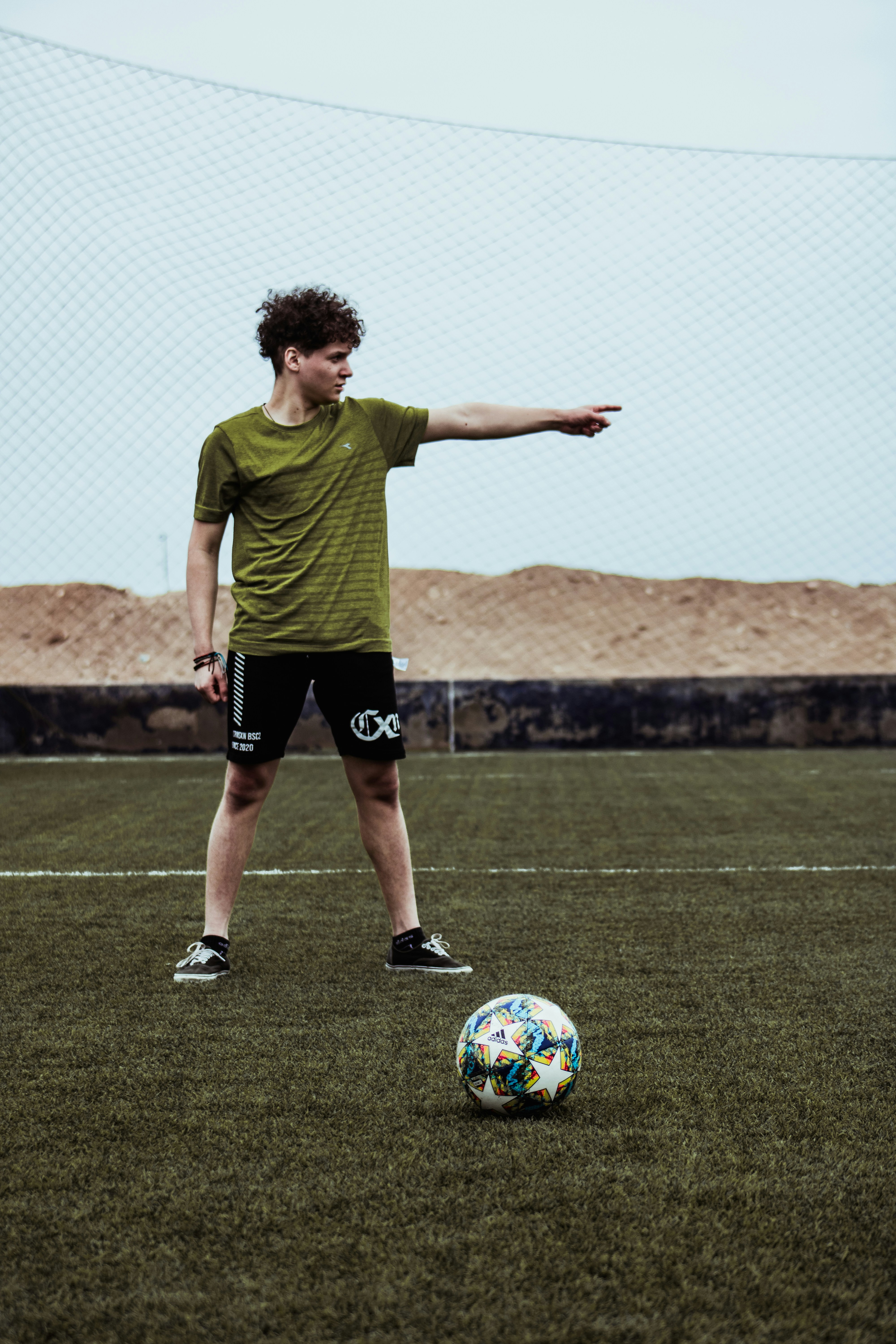man in green shirt and black shorts playing soccer during daytime