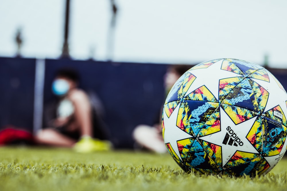 white blue and red soccer ball on green grass field during daytime