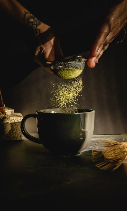 person pouring water on black ceramic mug