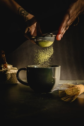 person pouring water on black ceramic mug