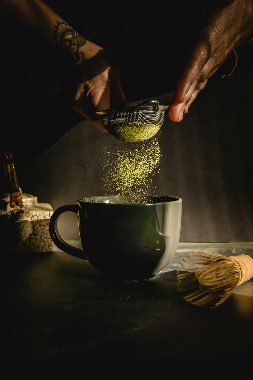 personne versant de l’eau sur une tasse en céramique noire