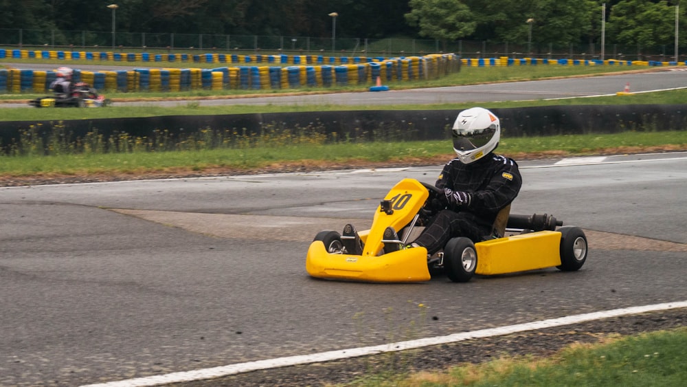 man in black helmet riding yellow and black go kart on gray asphalt road during daytime