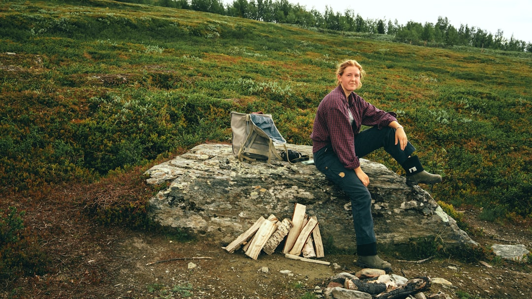 man in purple jacket and blue denim jeans standing on brown soil during daytime