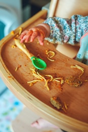 person holding brown wooden tray with green leaf