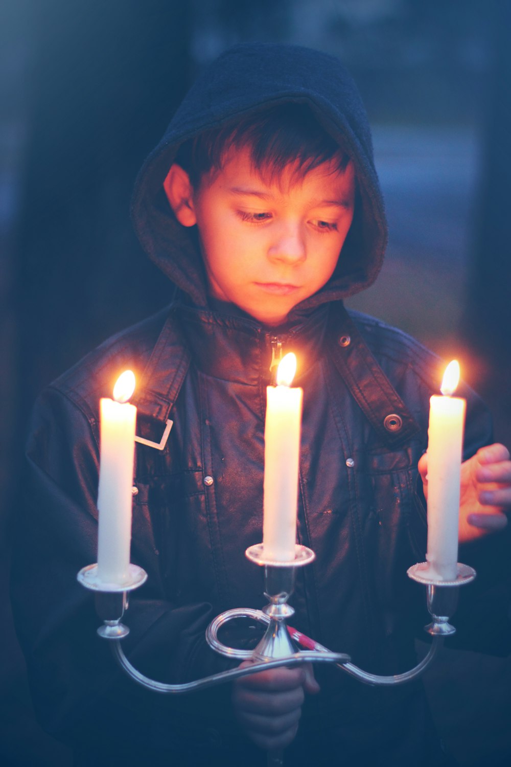 boy in gray hoodie holding lighted candles