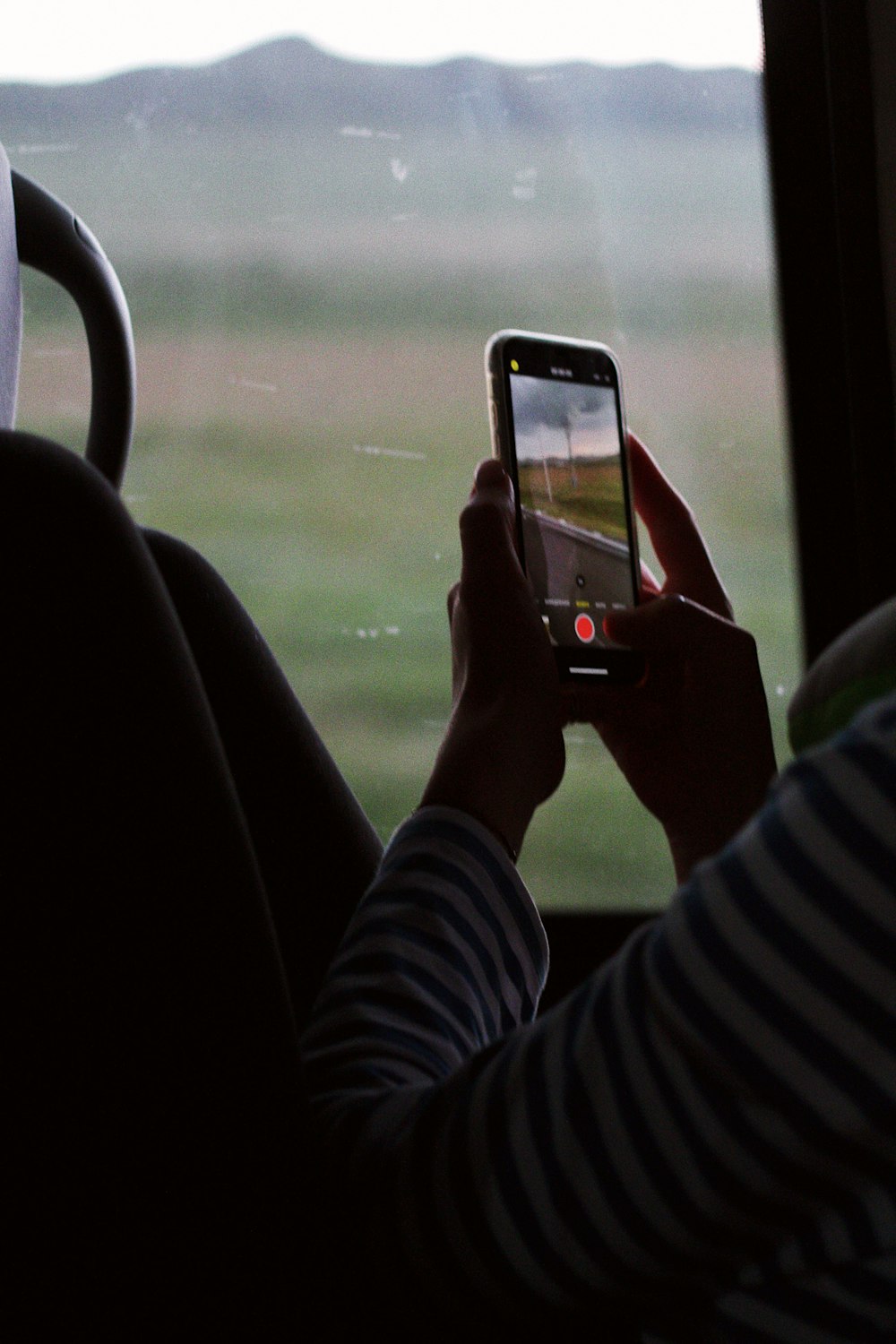 a person taking a picture of a field through a car window