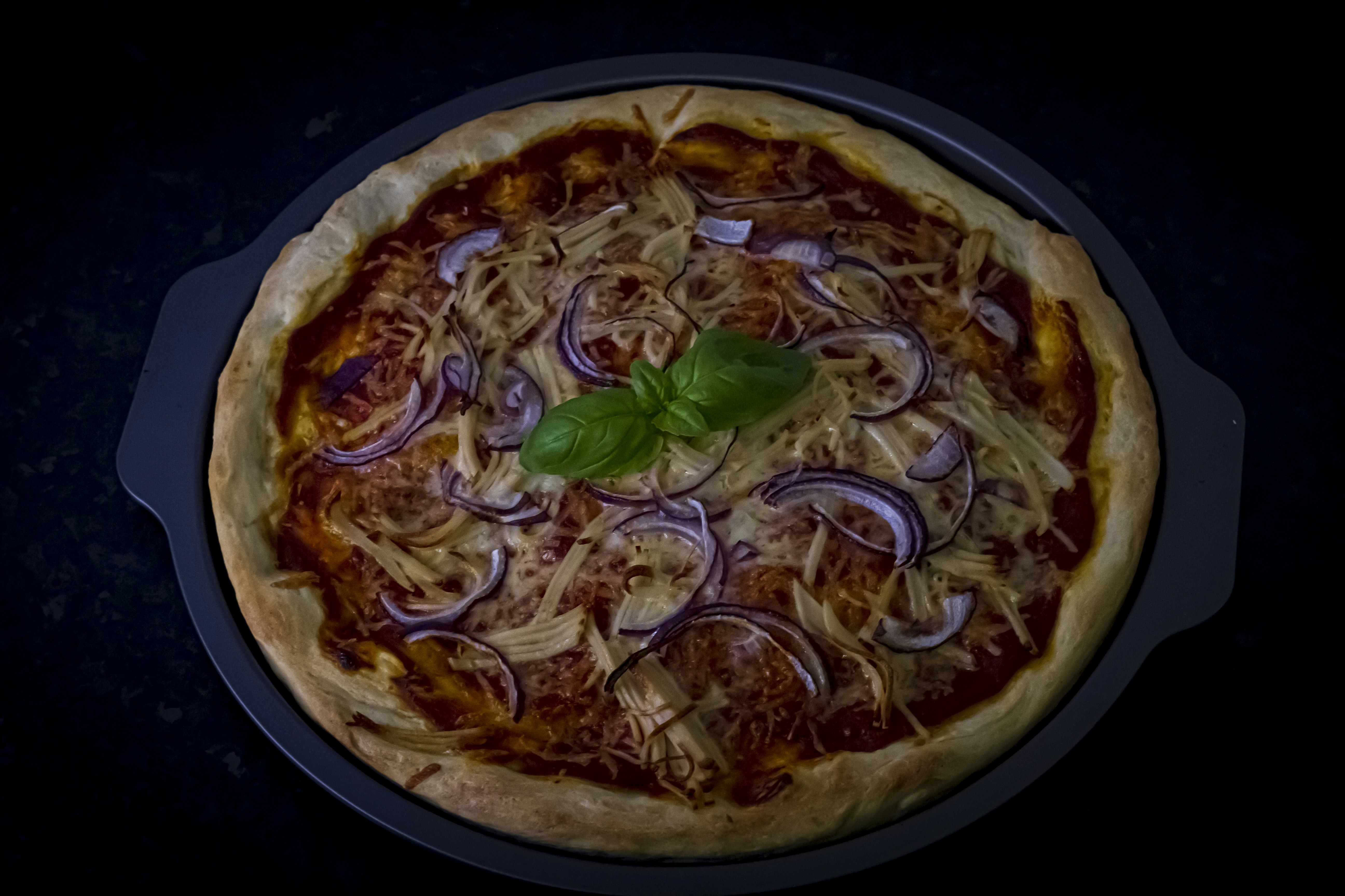pizza with green leaves on black plate