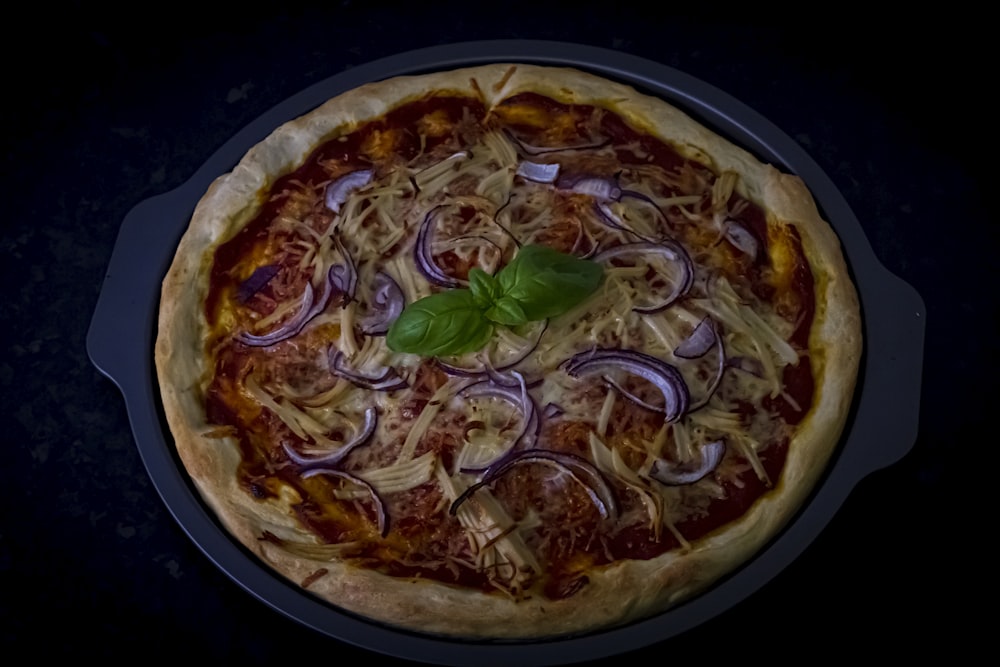 pizza with green leaves on black plate