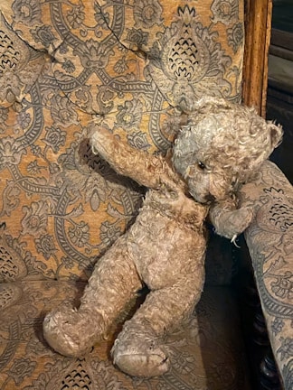 A velvet Elvis-style leisure suit designed for a stuffed animal, displayed on a vintage chair.