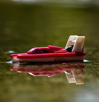 red and white plastic boat on water