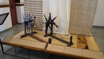 Historical spinning wheel next to raw wool and finished yarn skeins.