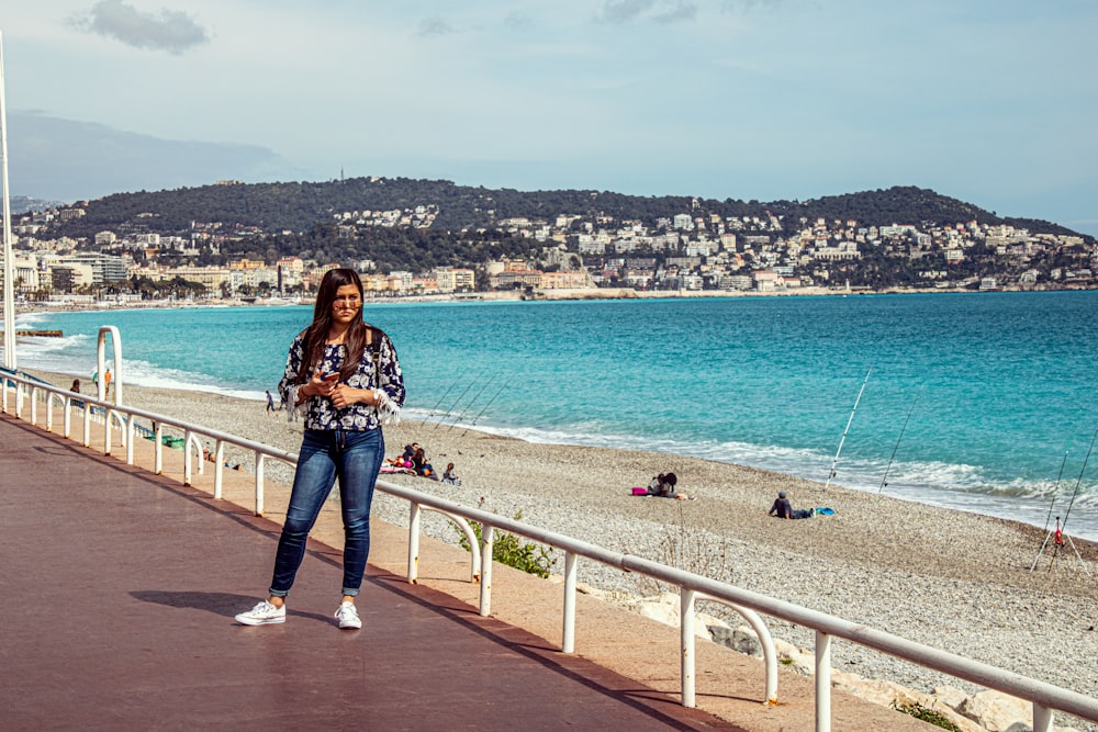 woman in black and white floral long sleeve shirt and blue denim jeans standing on white