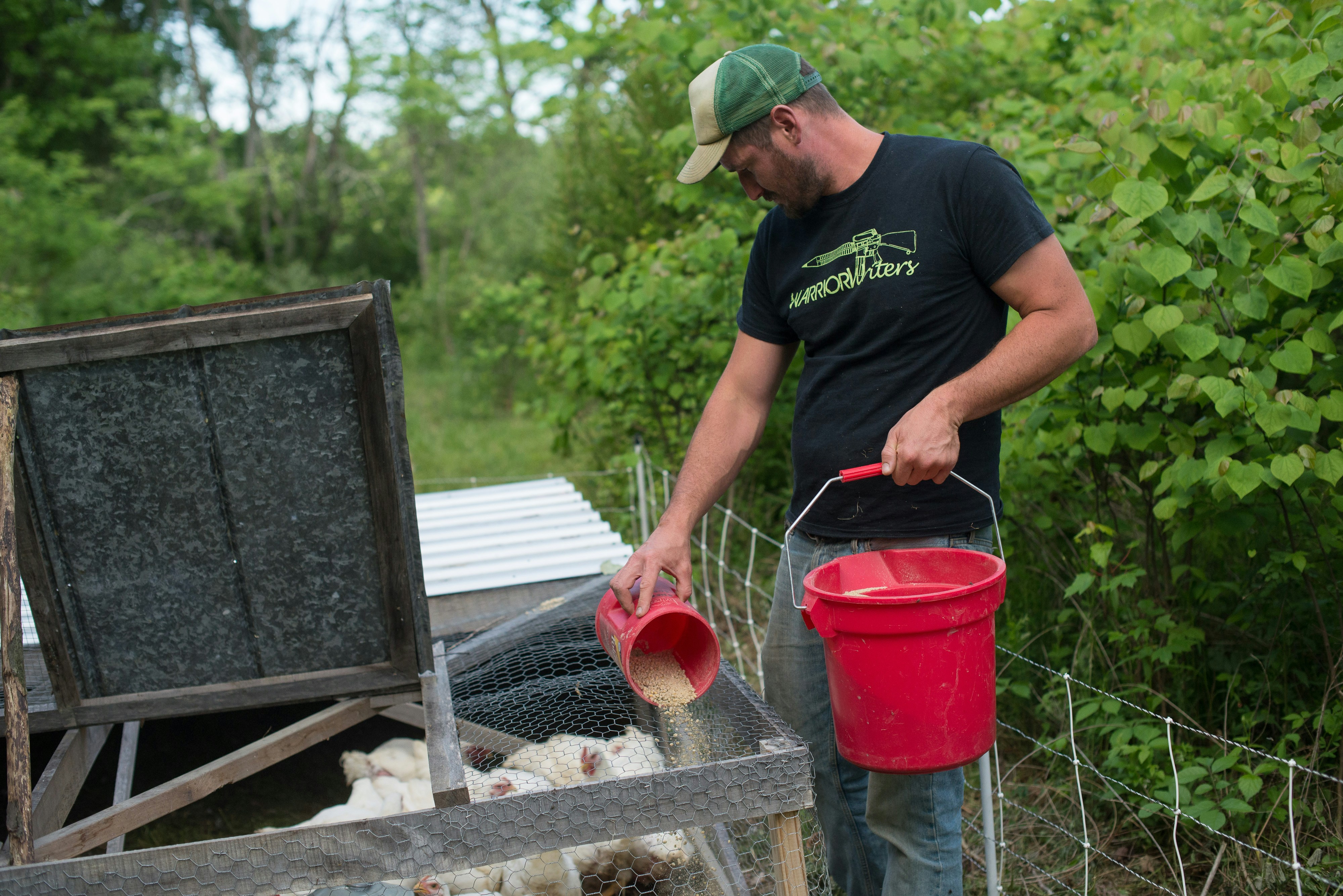 man in black crew neck t-shirt and blue denim jeans holding red plastic bucket