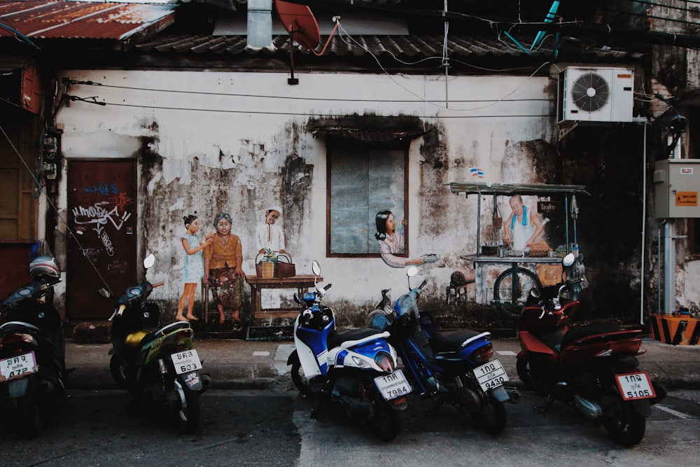 blue and white sports bike parked beside white concrete building during daytime