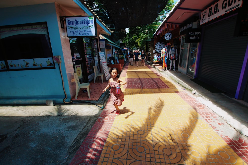 girl in pink dress sitting on brown concrete floor during daytime