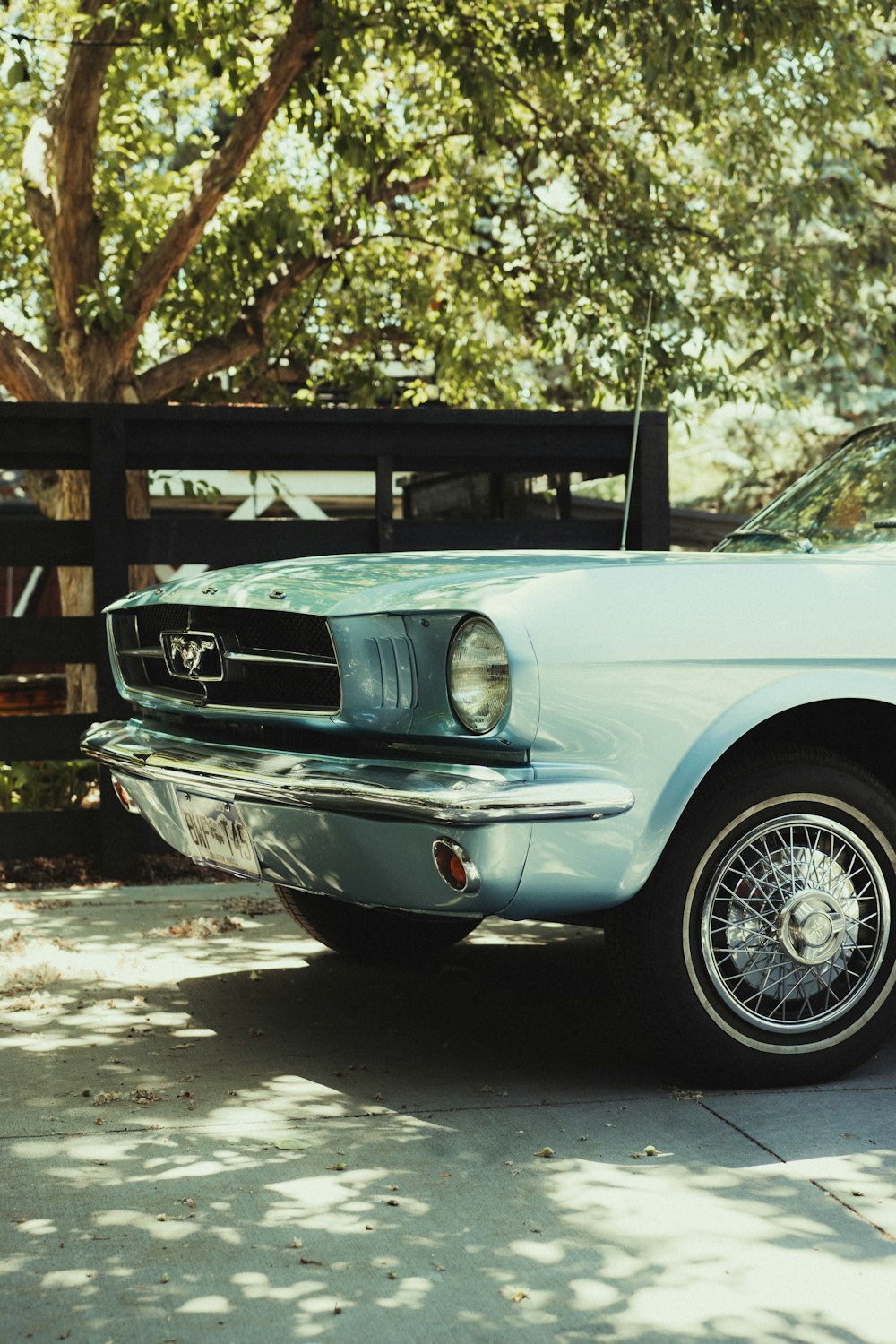 white classic car parked near brown wooden fence during daytime