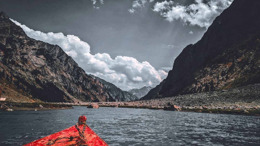 red kayak on lake near mountain under white clouds during daytime