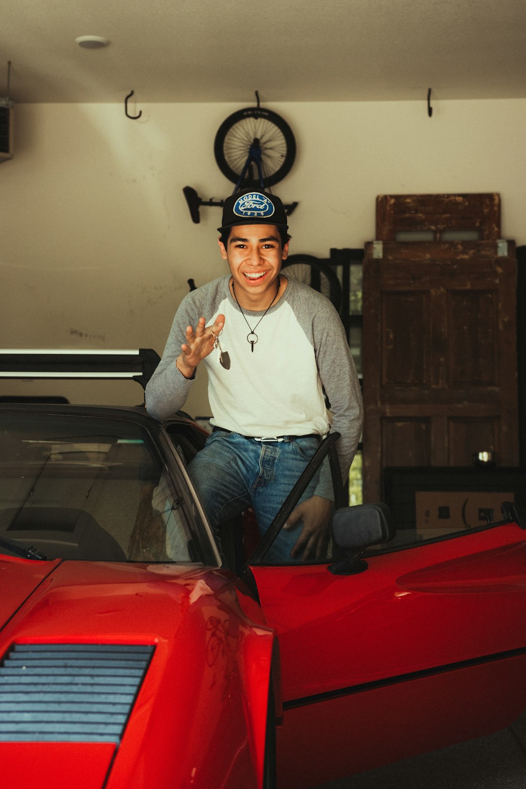 man in white long sleeve shirt and blue denim jeans standing beside red car