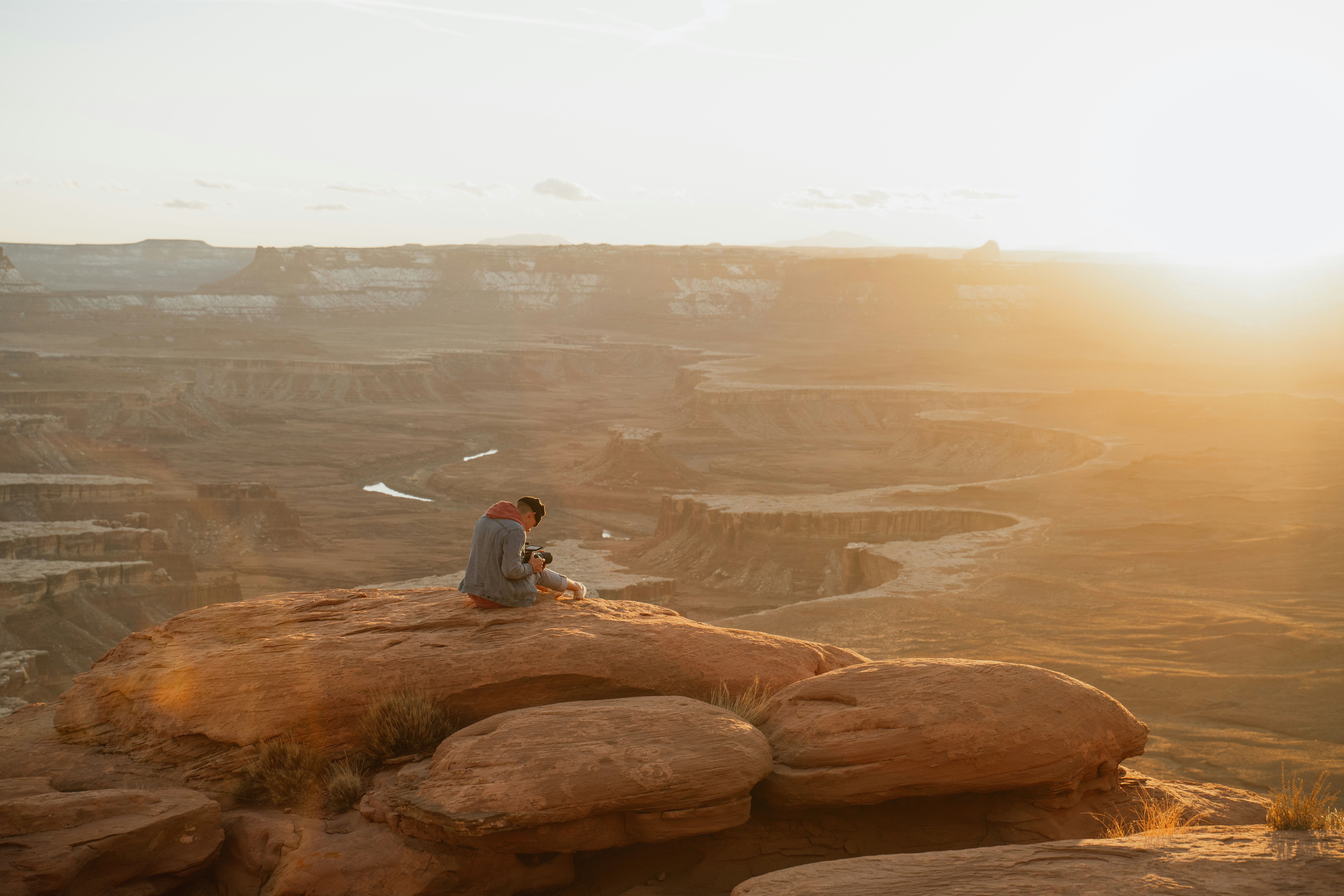 person in white shirt sitting on brown rock formation during daytime