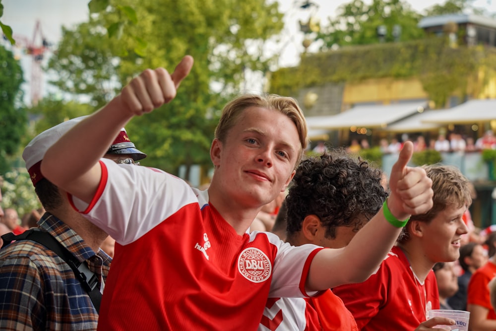 man in red and white nike crew neck t-shirt raising his hands