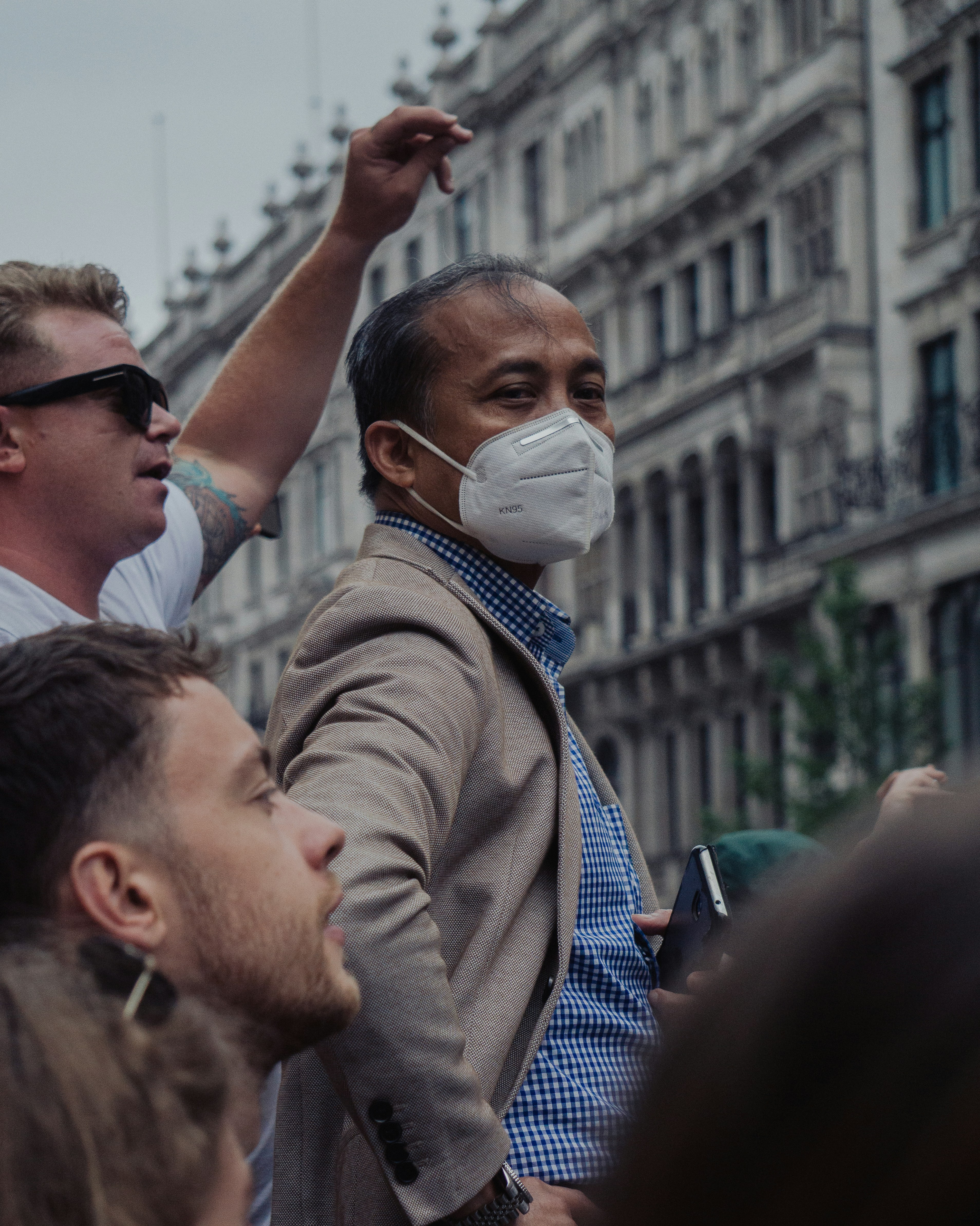 man in brown coat raising his hands
