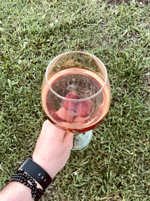 A lifestyle shot of a fan holding a rosévibe drinkware cup with pink and black accents.
