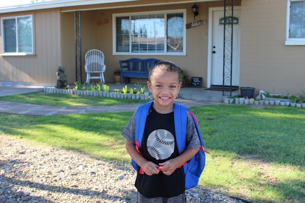Happy child holding a backpack filled with school essentials outdoors