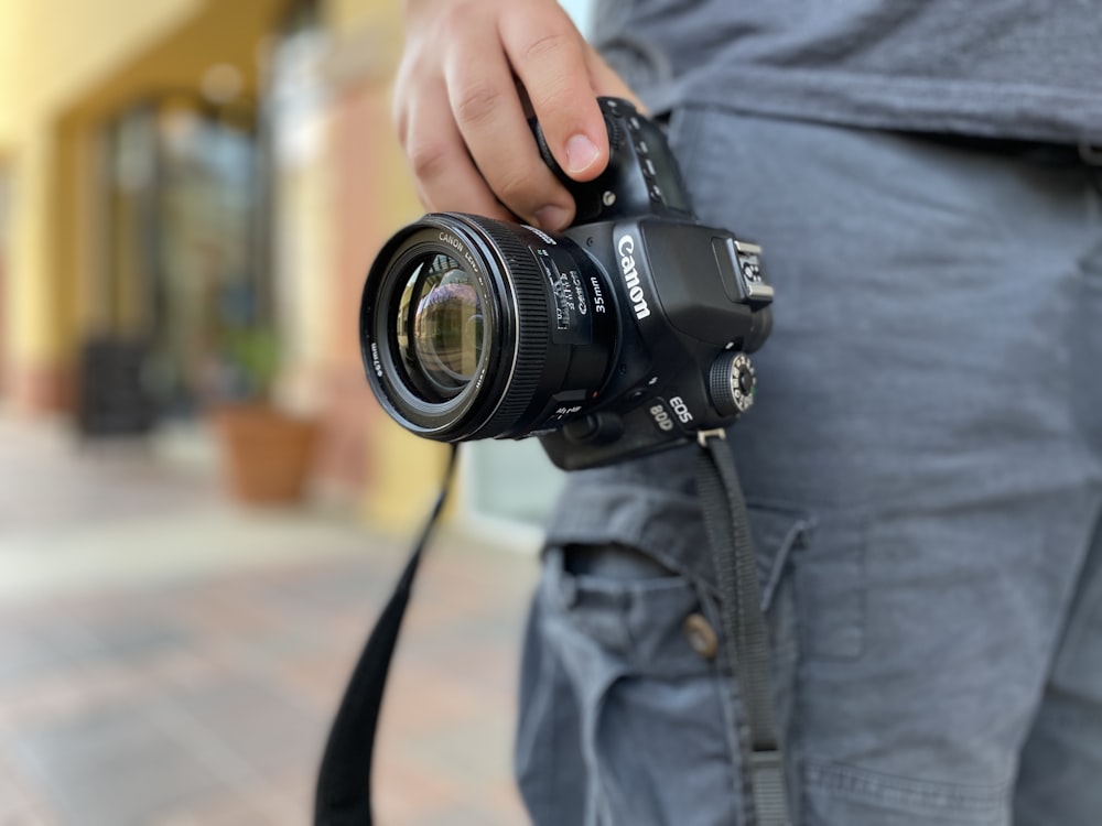 person in blue denim jacket holding black dslr camera