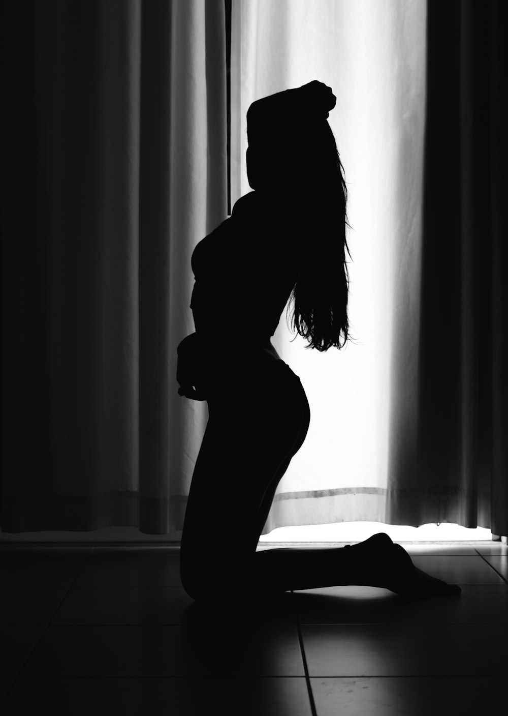 silhouette of woman standing in front of window curtain