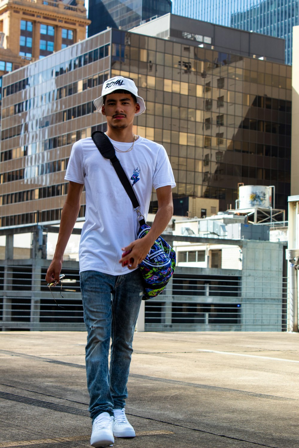 man in white crew neck t-shirt and blue denim jeans standing on brown concrete floor