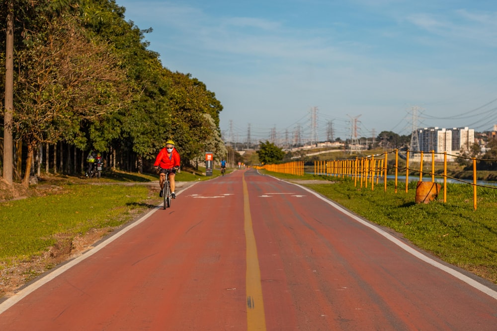 man in red shirt riding bicycle on road during daytime
