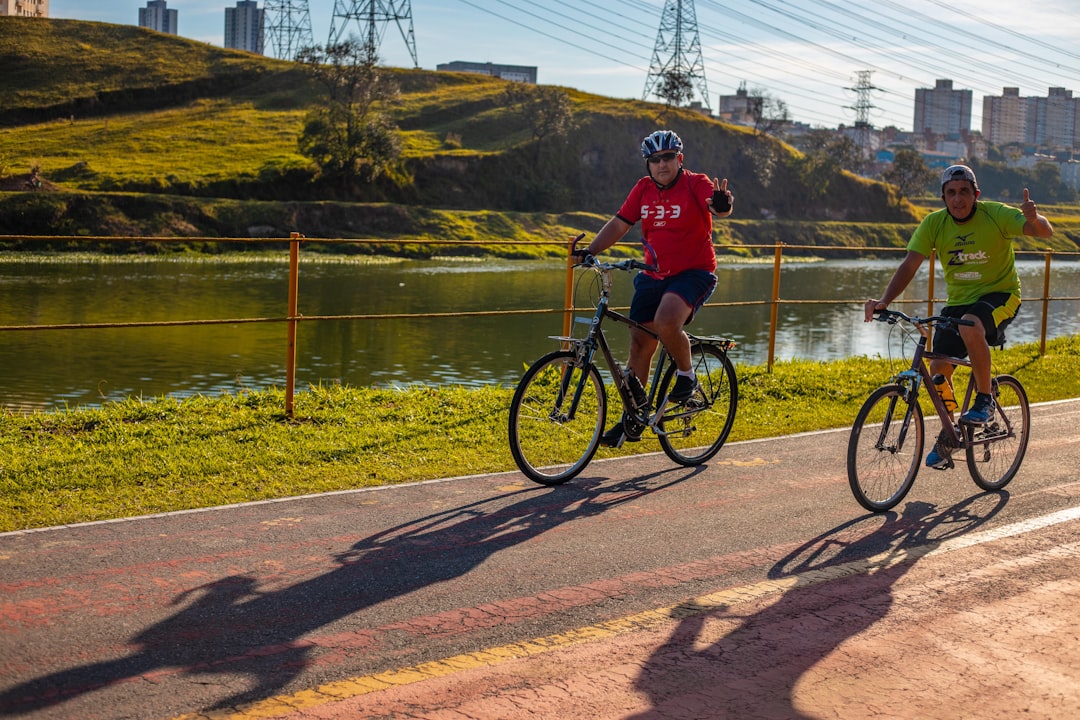 man in red shirt riding bicycle near lake during daytime